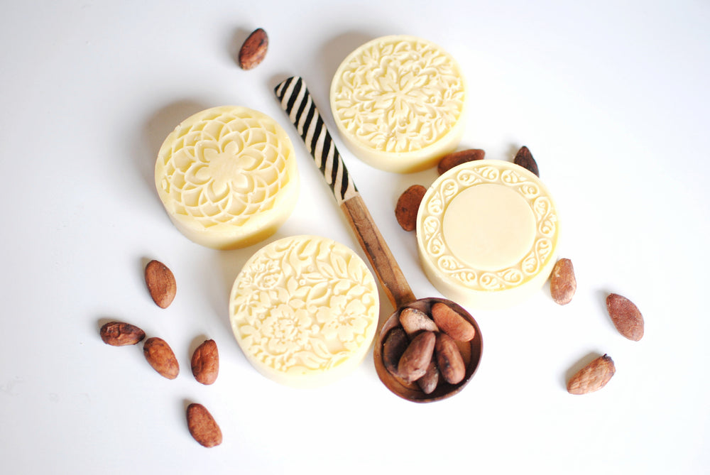 cooca butter lotion bars with cocoa beans on a spoon